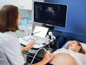 sage femme pratiquant une échographie de suivi obstétrique